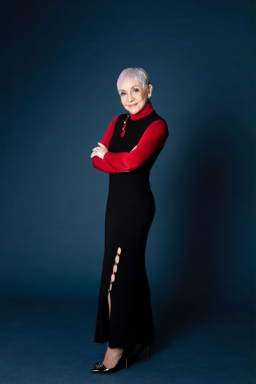 Cininha de Paula em corpo inteiro, vestido longo preto e blusa vermelha